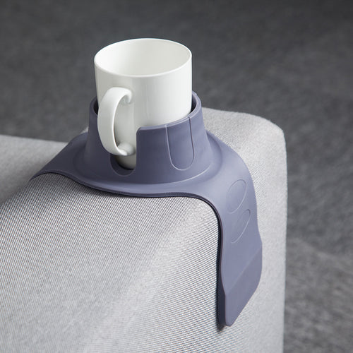 Silicone cup holder draped over a couch armrest with a drink in it